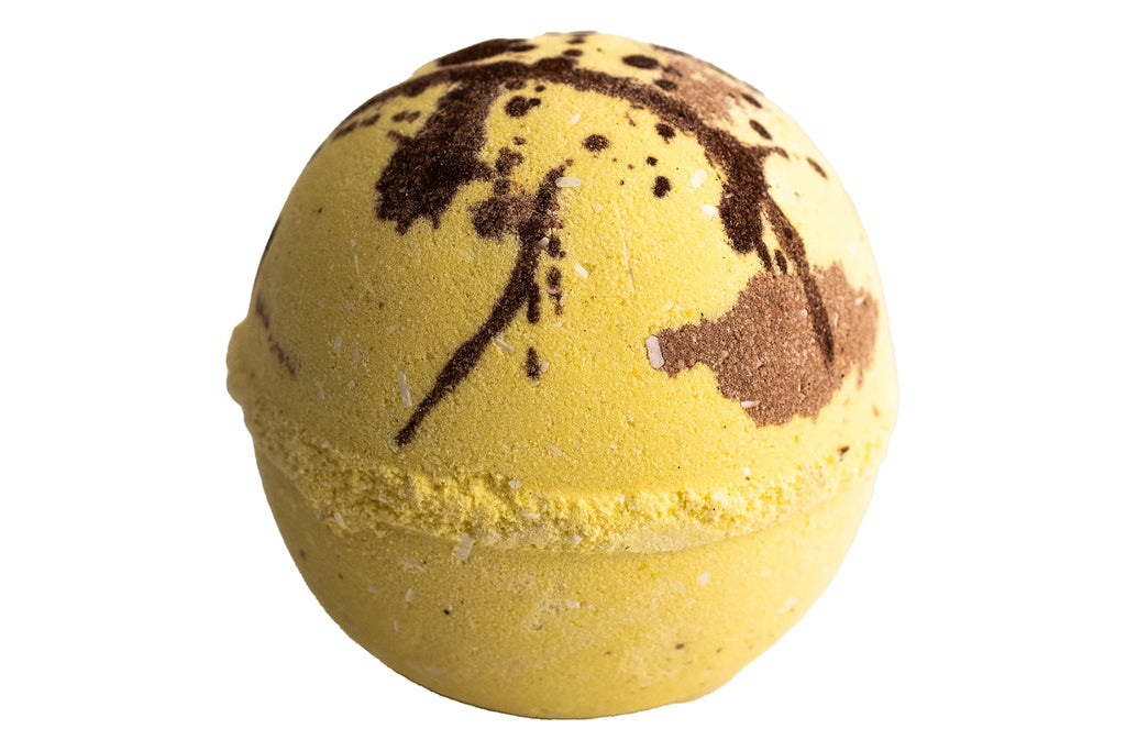 Yellow bath bomb with brown speckles on a white background
